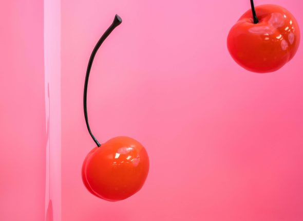 Dwie wiśnie na różowym tle. Ilustracja do tekstu: Kiedy jest dobry moment na drugi produkt cyfrowy